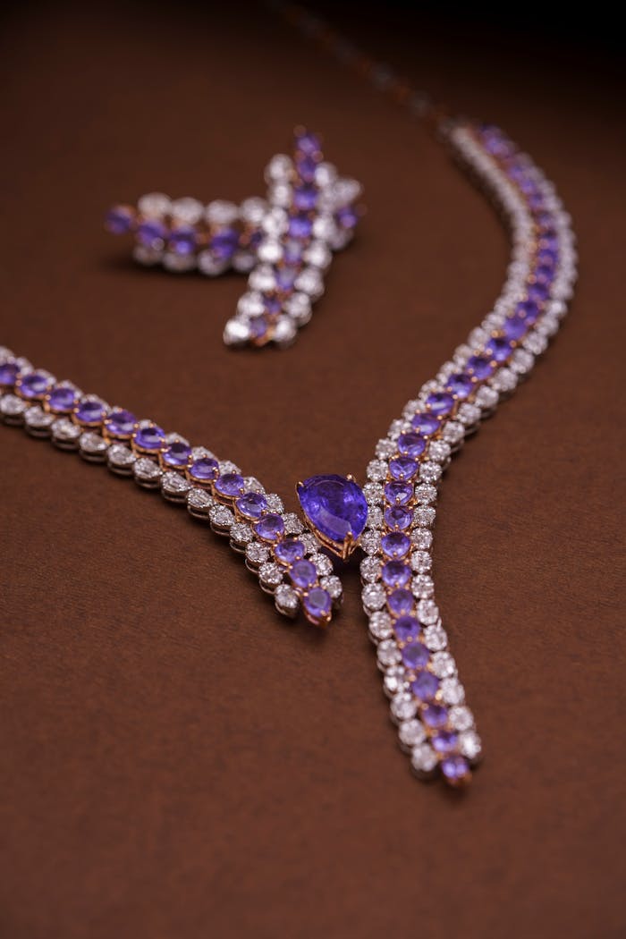 Luxury amethyst and diamond necklace and earring set on brown background.